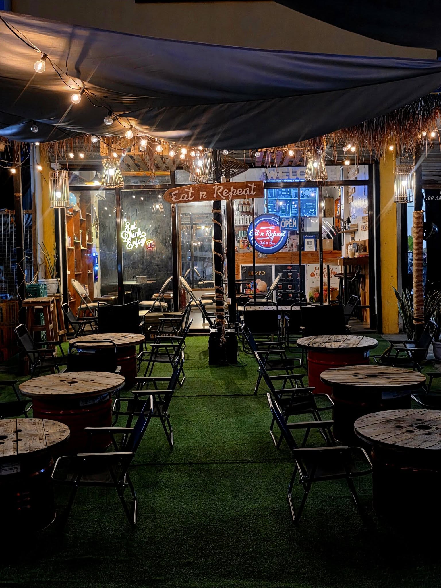 Eat n RepEat Cafe exterior with warm lights and wooden tables